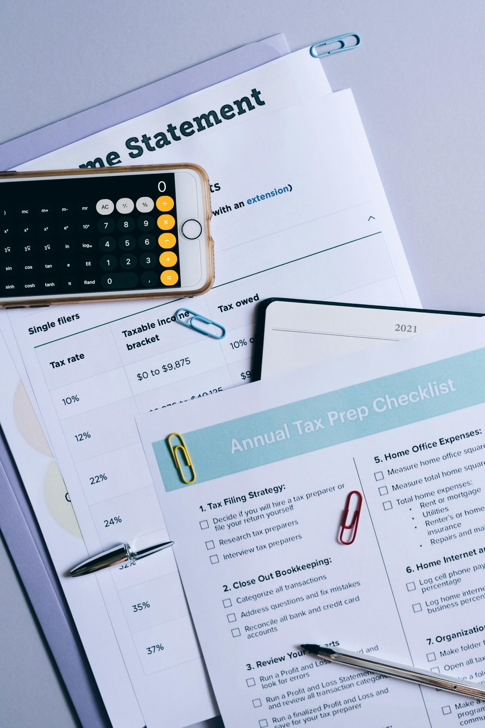 Flat lay of financial documents, tax checklist, and calculator for tax prep.